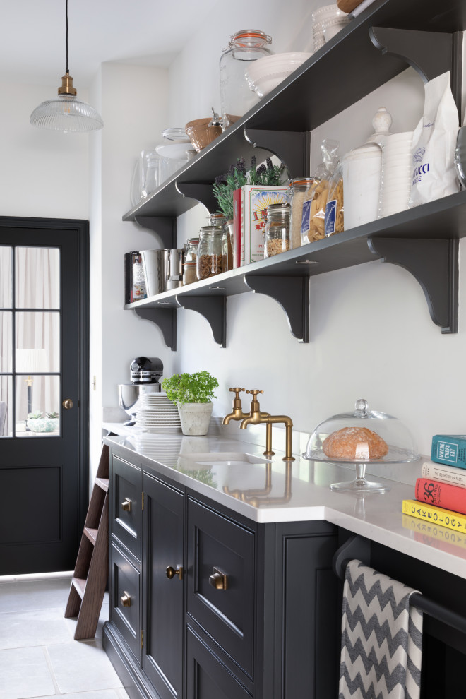 This is an example of a classic kitchen pantry in Surrey with a submerged sink, beaded cabinets, black cabinets, grey floors and white worktops.