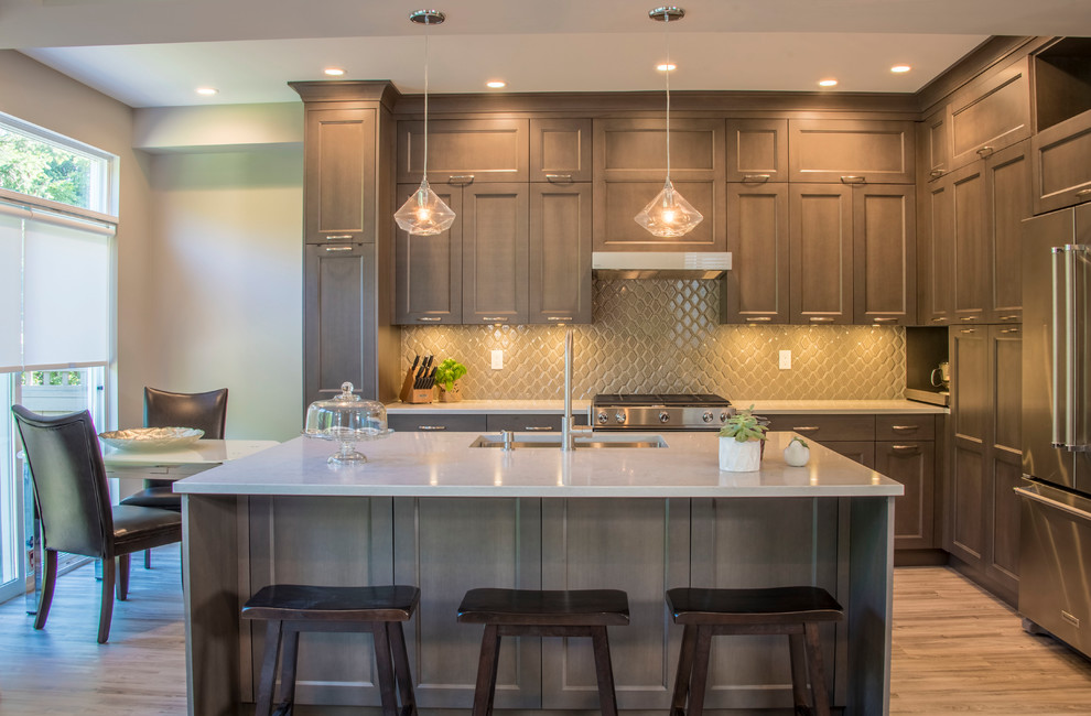 Medium sized traditional l-shaped kitchen/diner in Vancouver with a submerged sink, engineered stone countertops, ceramic splashback, stainless steel appliances, vinyl flooring, an island, brown floors, shaker cabinets, brown cabinets, grey splashback and grey worktops.