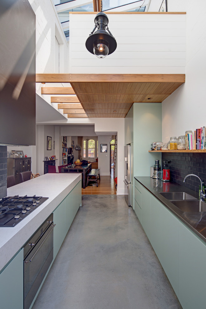 Inredning av ett modernt mellanstort kök och matrum, med en undermonterad diskho, släta luckor, gröna skåp, bänkskiva i betong, svart stänkskydd, stänkskydd i keramik, rostfria vitvaror, betonggolv och en köksö