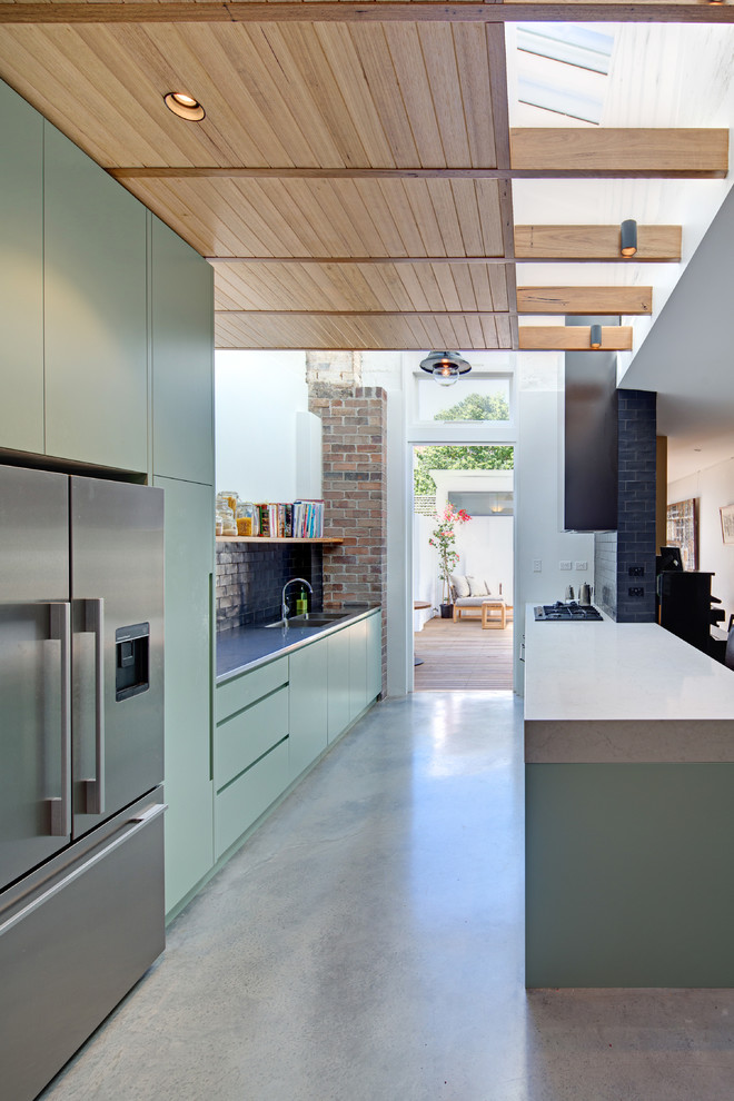 Exempel på ett mellanstort modernt kök, med en undermonterad diskho, släta luckor, gröna skåp, bänkskiva i betong, svart stänkskydd, stänkskydd i keramik, rostfria vitvaror, betonggolv och en köksö