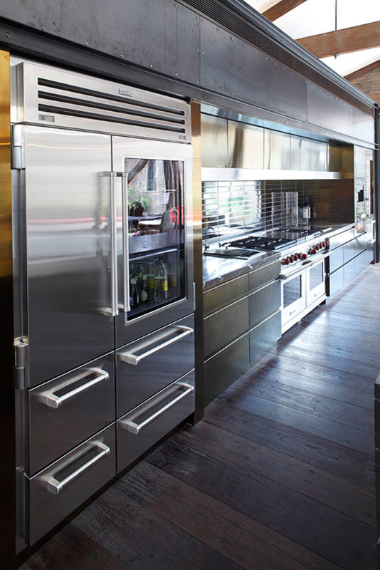 Esempio di una grande cucina eclettica con ante lisce, paraspruzzi con piastrelle di metallo, elettrodomestici in acciaio inossidabile, pavimento in legno massello medio e 2 o più isole