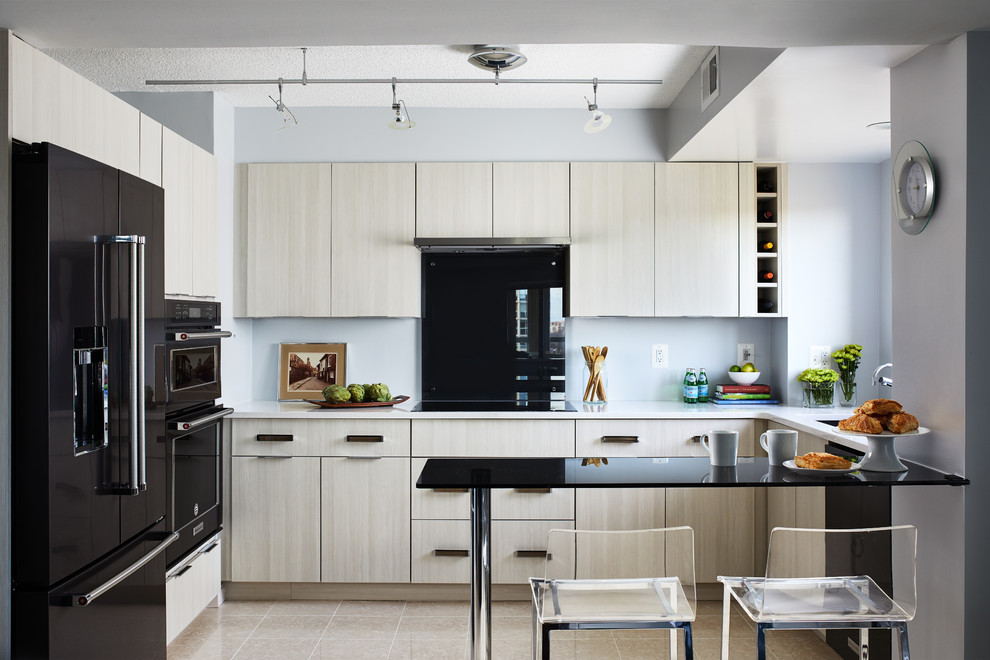 Idéer för ett modernt vit l-kök, med en undermonterad diskho, släta luckor, bänkskiva i kvarts, grått stänkskydd, glaspanel som stänkskydd, en halv köksö, beiget golv, svarta vitvaror och skåp i ljust trä