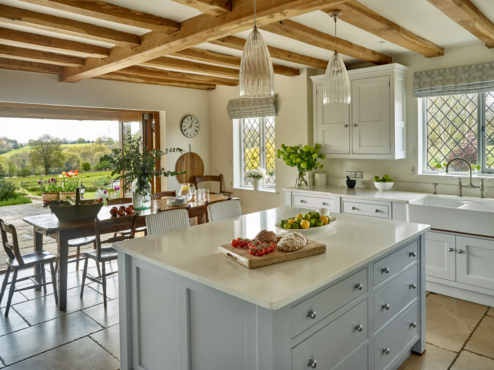 Mittelgroße Landhaus Wohnküche mit Landhausspüle, Schrankfronten im Shaker-Stil, blauen Schränken, Kücheninsel und beigem Boden in Sussex