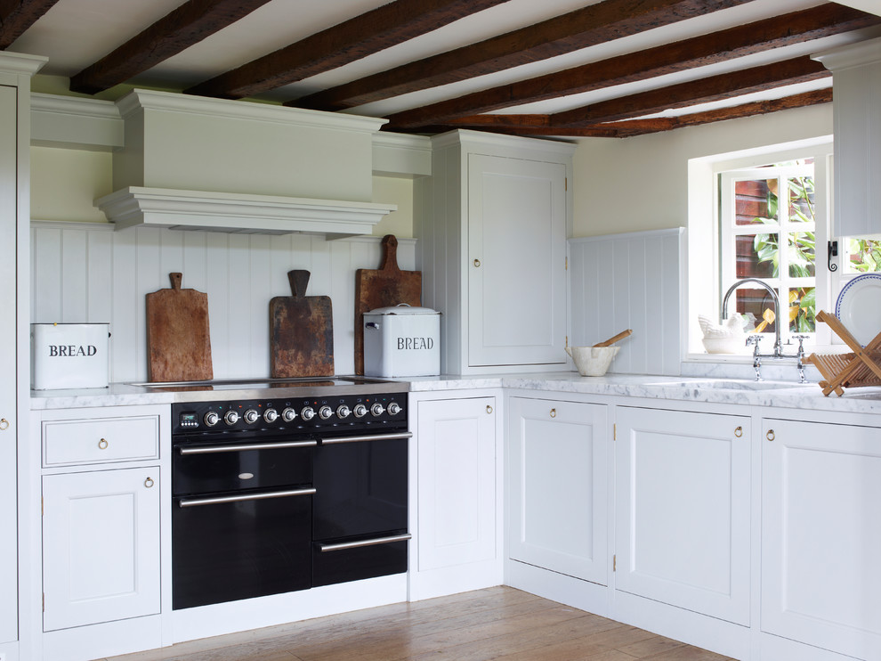 Réalisation d'une cuisine champêtre avec des portes de placard blanches et plan de travail en marbre.