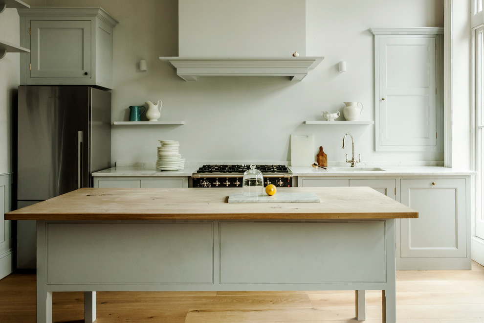 ロンドンにあるトラディショナルスタイルのおしゃれなキッチン (シングルシンク、落し込みパネル扉のキャビネット、白いキャビネット、シルバーの調理設備、淡色無垢フローリング) の写真