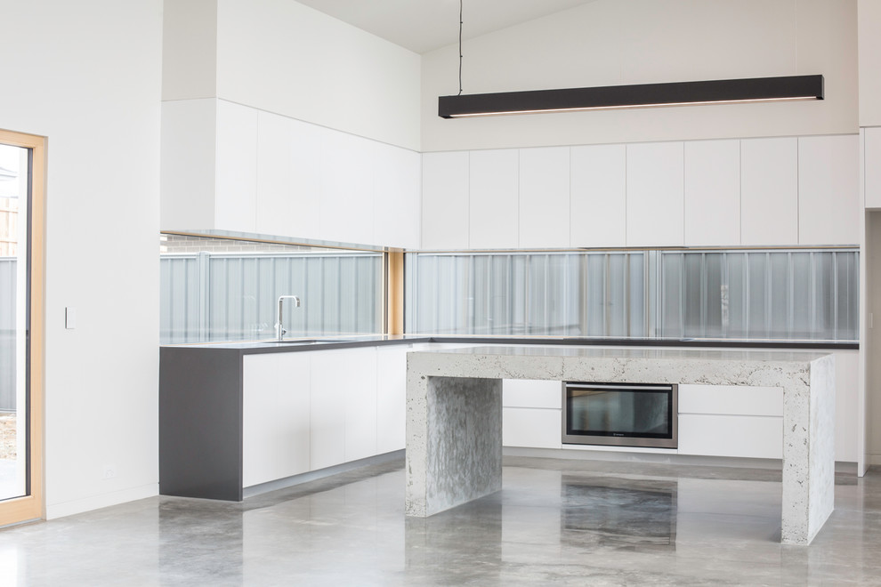 Inspiration för stora moderna grått kök, med en undermonterad diskho, släta luckor, vita skåp, bänkskiva i betong, fönster som stänkskydd, rostfria vitvaror, betonggolv, en köksö och grått golv