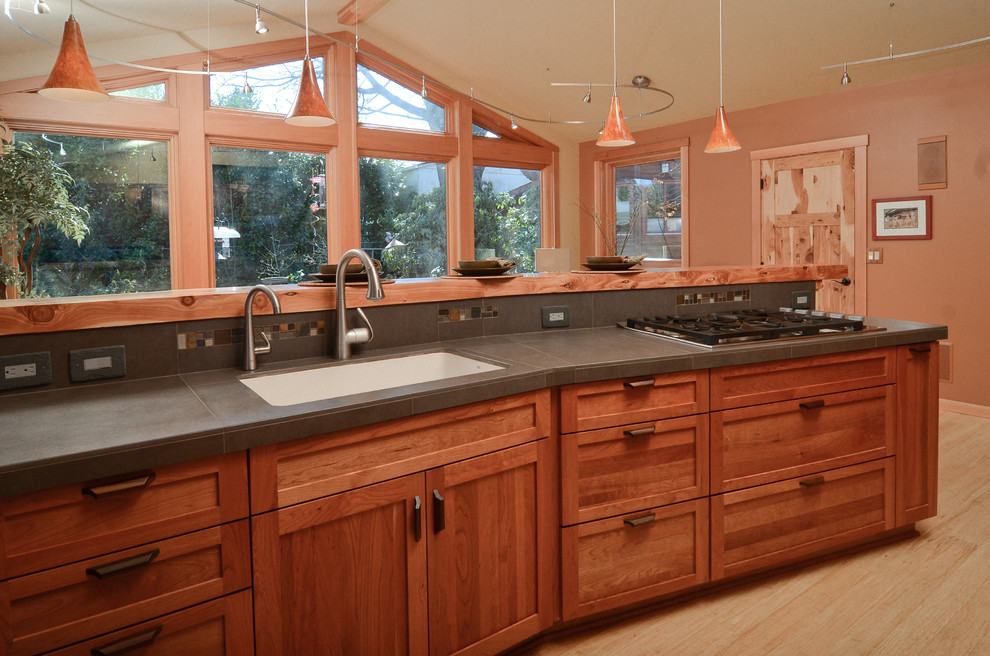 Example of an arts and crafts u-shaped bamboo floor kitchen design in Portland with an undermount sink, shaker cabinets, medium tone wood cabinets, tile countertops, gray backsplash, porcelain backsplash and stainless steel appliances