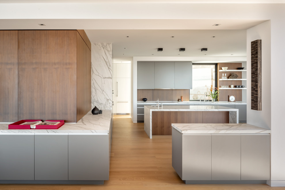Idéer för ett mycket stort modernt vit kök med öppen planlösning, med släta luckor, en undermonterad diskho, grå skåp, mellanmörkt trägolv, en köksö och brunt golv