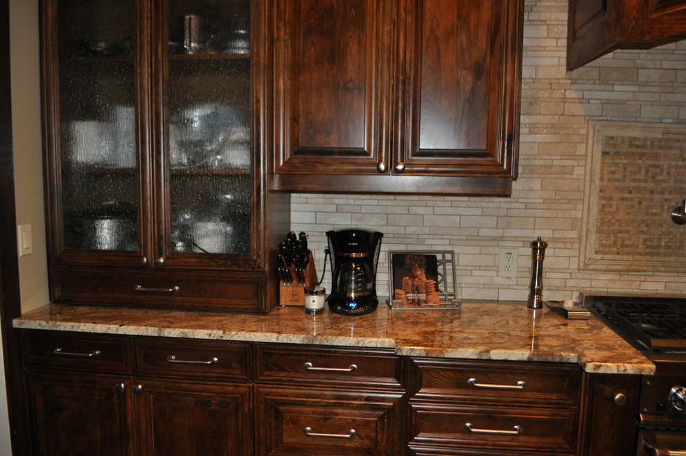 Example of a large classic medium tone wood floor kitchen design in Dallas with an undermount sink, shaker cabinets, medium tone wood cabinets, granite countertops, beige backsplash, stone tile backsplash and stainless steel appliances