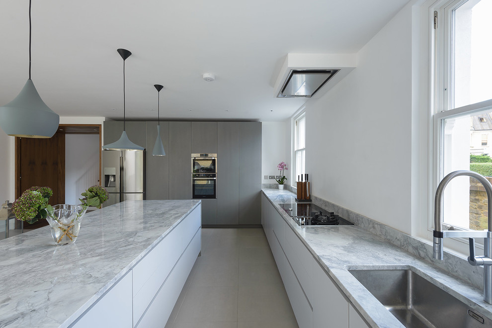 Photo of a large contemporary l-shaped open plan kitchen in London with a single-bowl sink, flat-panel cabinets, white cabinets, marble worktops, stainless steel appliances and an island.