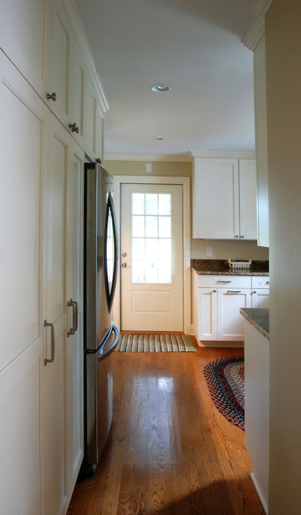 Idée de décoration pour une cuisine champêtre avec un placard avec porte à panneau encastré, des portes de placard blanches et un sol en bois brun.