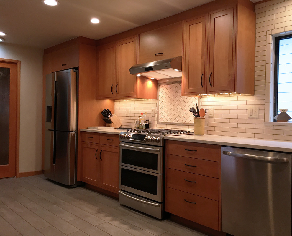 他の地域にある高級な中くらいなミッドセンチュリースタイルのおしゃれなキッチン (一体型シンク、フラットパネル扉のキャビネット、中間色木目調キャビネット、ソープストーンカウンター、白いキッチンパネル、セラミックタイルのキッチンパネル、シルバーの調理設備、セラミックタイルの床、アイランドなし、グレーの床) の写真