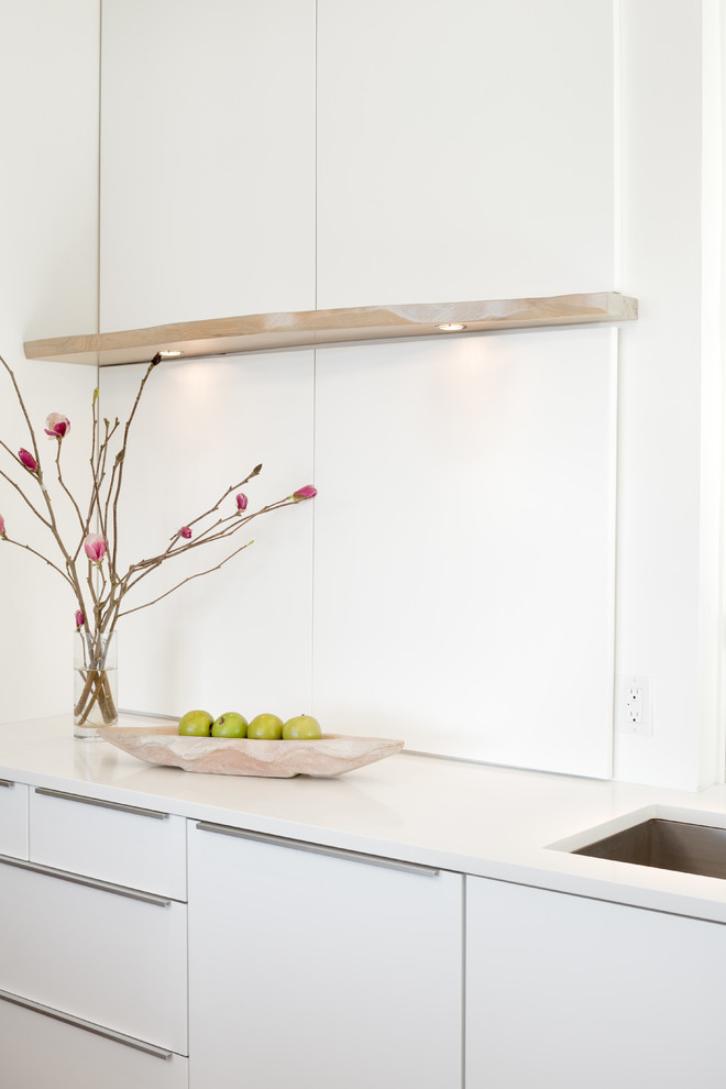 Ejemplo de cocina comedor minimalista con armarios con paneles lisos, puertas de armario blancas y una isla
