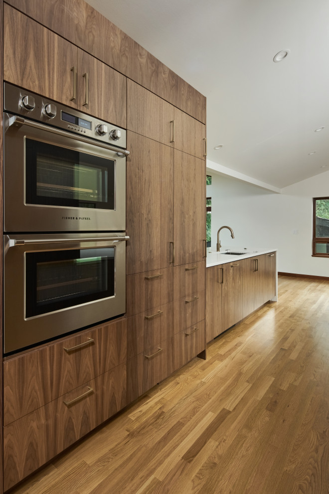 Inspiration pour une grande cuisine américaine parallèle minimaliste en bois brun avec un évier encastré, un placard à porte plane, un plan de travail en bois, un sol en bois brun, aucun îlot, un plan de travail blanc et un plafond voûté.
