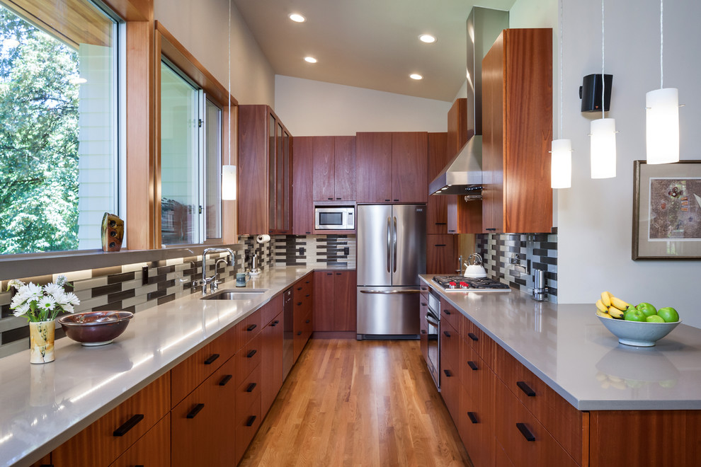 Example of a large minimalist u-shaped medium tone wood floor and beige floor eat-in kitchen design in Portland with an undermount sink, flat-panel cabinets, gray backsplash, ceramic backsplash, stainless steel appliances, no island, dark wood cabinets and solid surface countertops
