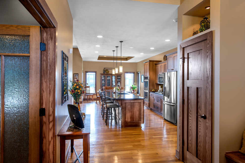 Immagine di una cucina country con lavello sottopiano, ante in legno scuro, top in granito, elettrodomestici in acciaio inossidabile e parquet chiaro