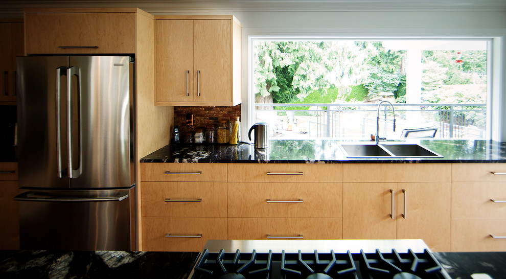 Foto de cocina moderna extra grande con fregadero encastrado, armarios con paneles lisos, puertas de armario de madera clara, encimera de granito, salpicadero multicolor, salpicadero de azulejos de vidrio, electrodomésticos de acero inoxidable, suelo de madera en tonos medios y una isla