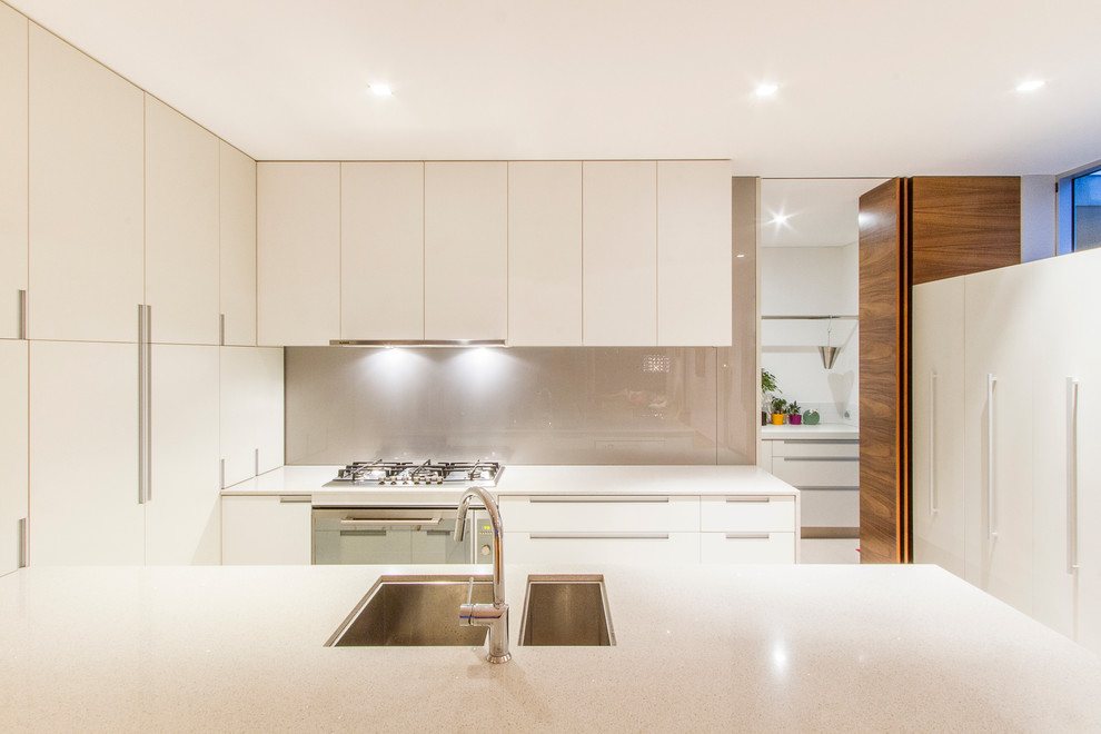 Стильный дизайн: параллельная кухня среднего размера в современном стиле с врезной мойкой, плоскими фасадами, белыми фасадами, серым фартуком и полуостровом - последний тренд