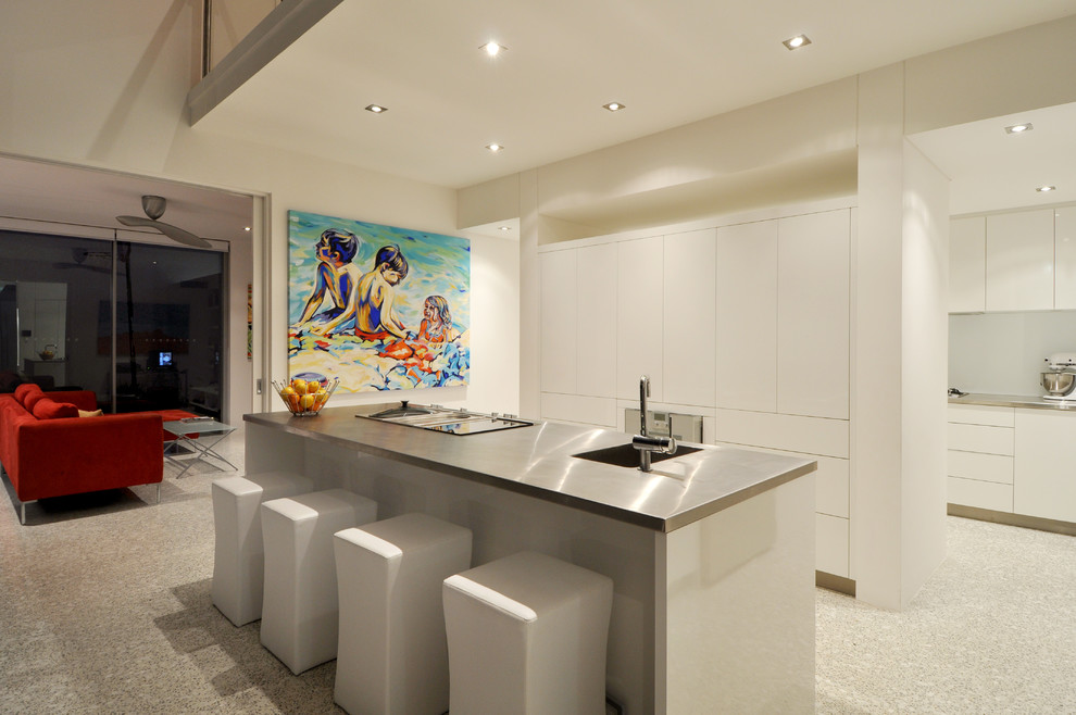 Foto de cocina contemporánea abierta con fregadero integrado, armarios con paneles lisos, puertas de armario blancas, encimera de acero inoxidable y una isla