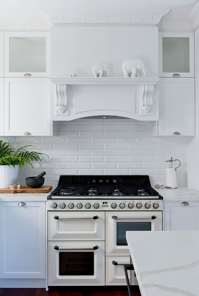 Imagen de cocina clásica con armarios estilo shaker, puertas de armario blancas, salpicadero blanco, salpicadero de azulejos tipo metro y electrodomésticos blancos