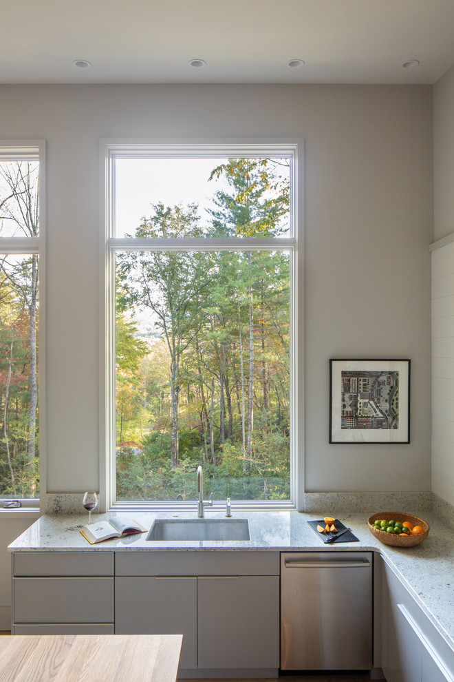 Exempel på ett mellanstort 50 tals grå grått kök, med en undermonterad diskho, släta luckor, grå skåp, bänkskiva i kvarts, rostfria vitvaror, mellanmörkt trägolv, en köksö och brunt golv