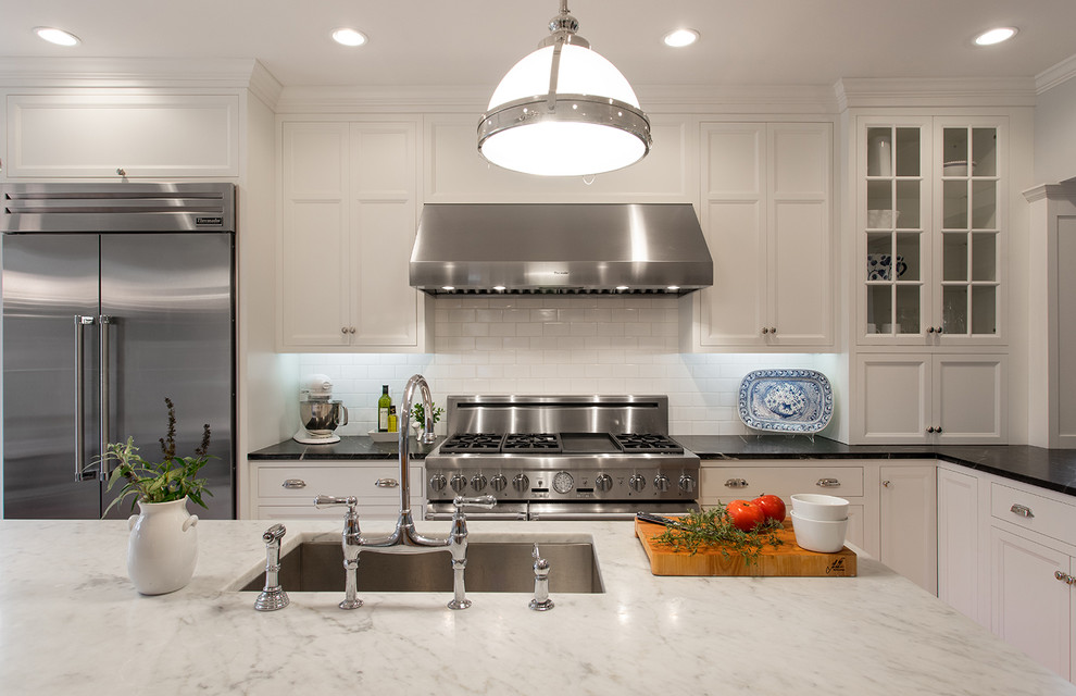 Inspiration for a farmhouse l-shaped kitchen in Boston with a submerged sink, recessed-panel cabinets, white splashback, metro tiled splashback, stainless steel appliances and an island.