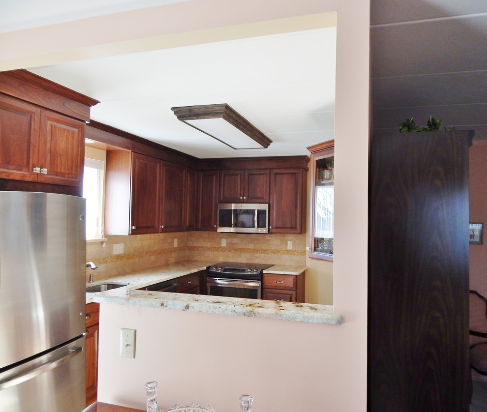 Photo of a small classic l-shaped enclosed kitchen in Philadelphia with a submerged sink, raised-panel cabinets, dark wood cabinets, granite worktops, beige splashback, stone tiled splashback, stainless steel appliances, a breakfast bar, porcelain flooring and beige floors.
