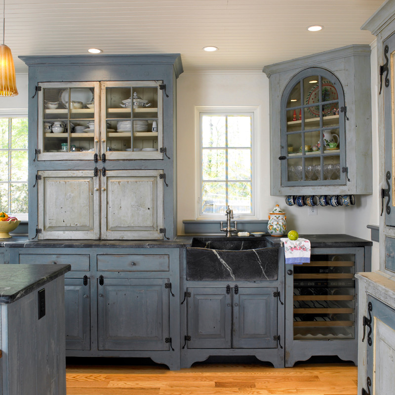 Example of a large country single-wall light wood floor and brown floor eat-in kitchen design in Philadelphia with a single-bowl sink, blue cabinets, white backsplash, stainless steel appliances, an island, soapstone countertops and raised-panel cabinets