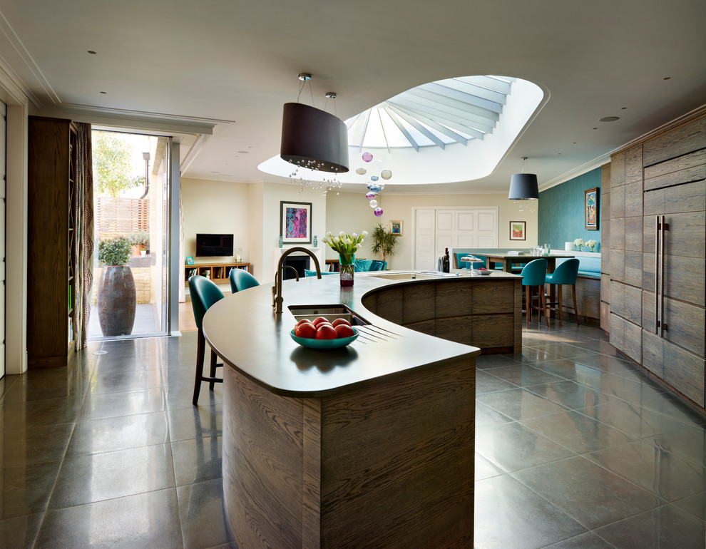 Large contemporary open plan kitchen in London with flat-panel cabinets, dark wood cabinets, composite countertops, integrated appliances and an island.