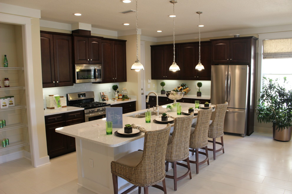 Mid-sized beach style l-shaped kitchen photo in Other with raised-panel cabinets, dark wood cabinets, granite countertops, an island and white countertops