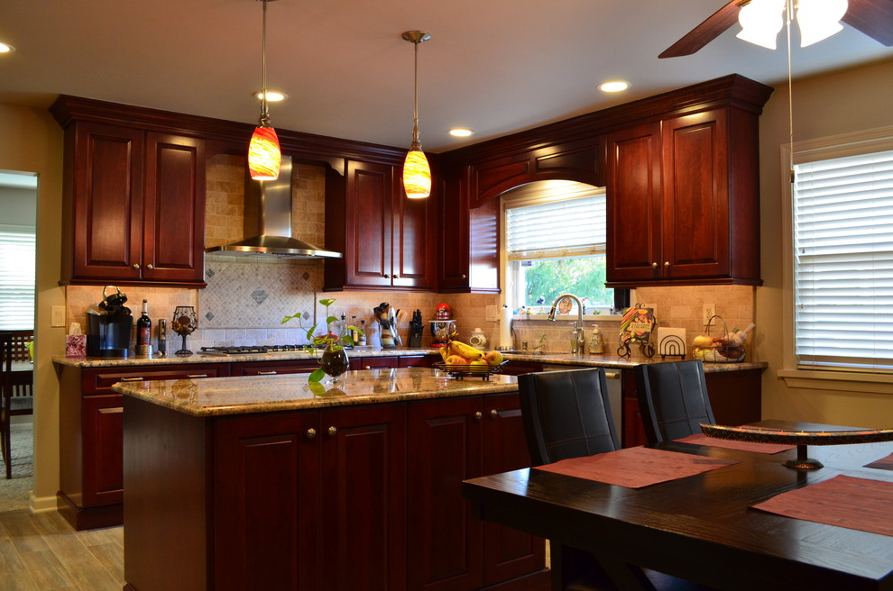 Immagine di una cucina con ante con bugna sagomata, top in granito, paraspruzzi beige, elettrodomestici in acciaio inossidabile e ante in legno bruno