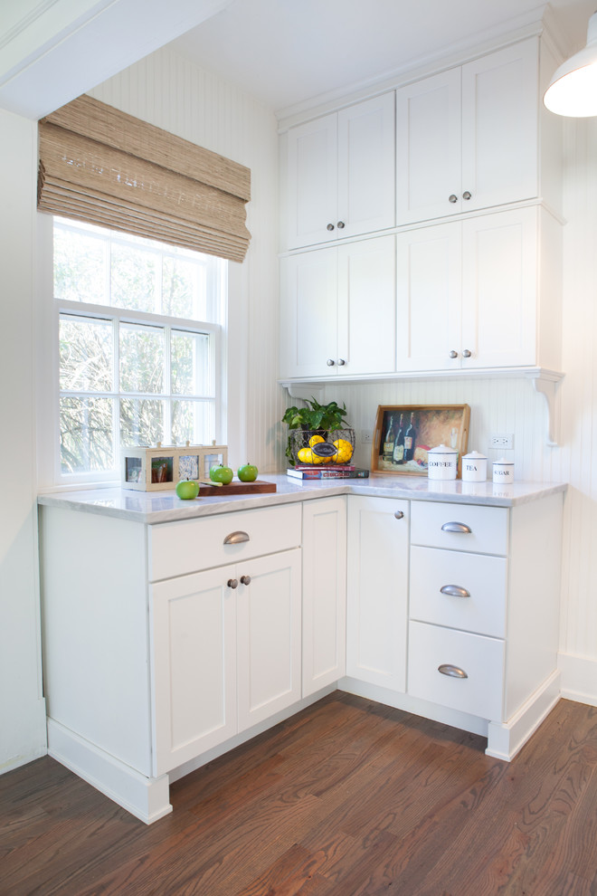 Inredning av ett lantligt litet linjärt kök och matrum, med en undermonterad diskho, luckor med infälld panel, vita skåp, vitt stänkskydd, rostfria vitvaror, mellanmörkt trägolv och marmorbänkskiva