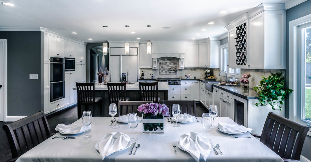 This is an example of a large traditional u-shaped kitchen/diner in San Francisco with a belfast sink, recessed-panel cabinets, white cabinets, engineered stone countertops, beige splashback, stone tiled splashback, stainless steel appliances, dark hardwood flooring and an island.