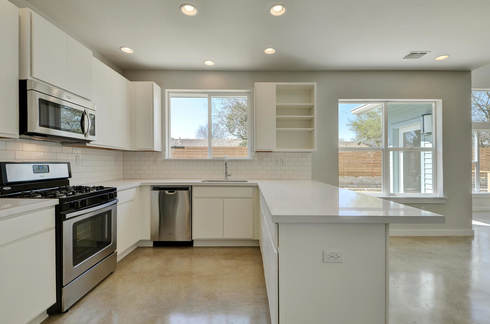 Mittelgroße Moderne Wohnküche mit Landhausspüle, weißen Schränken, Küchenrückwand in Weiß, Rückwand aus Metrofliesen, Küchengeräten aus Edelstahl, Betonboden und Halbinsel in Austin