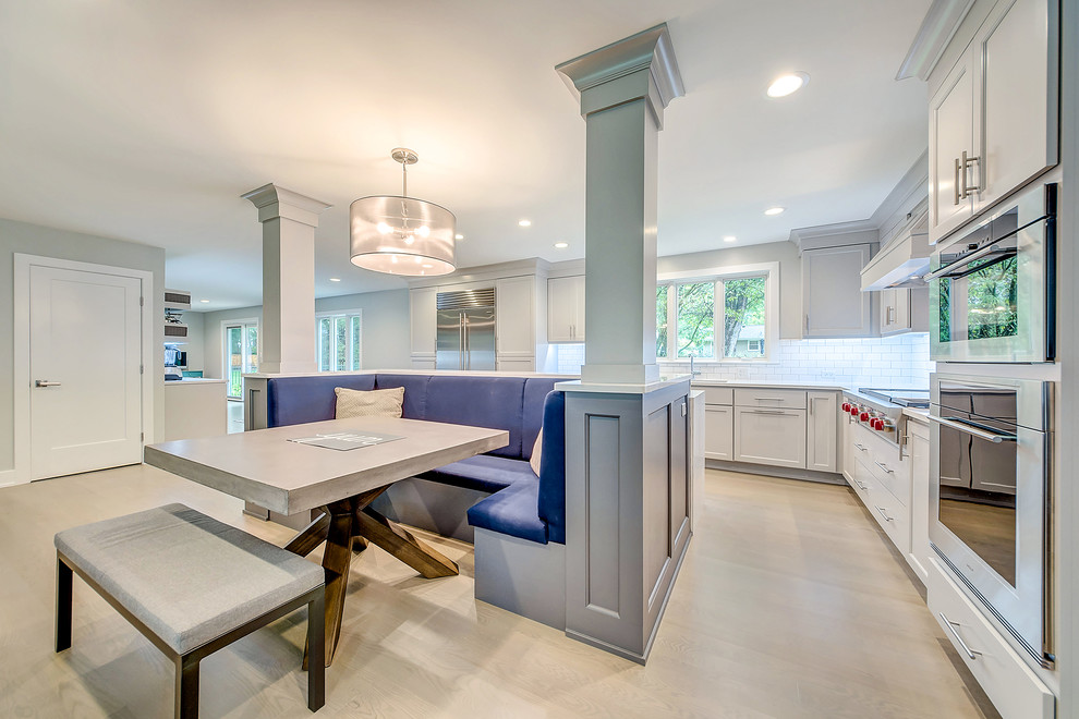 Example of a trendy light wood floor open concept kitchen design in Chicago with white backsplash, subway tile backsplash, stainless steel appliances and an island