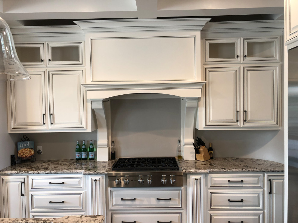 Example of a large trendy enclosed kitchen design in Sacramento with raised-panel cabinets, white cabinets and an island