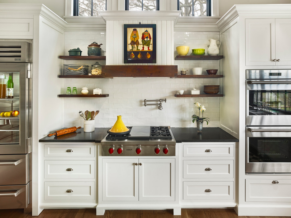 Bild på ett stort lantligt kök, med skåp i shakerstil, vita skåp, vitt stänkskydd, rostfria vitvaror, mörkt trägolv, en undermonterad diskho, träbänkskiva och en köksö