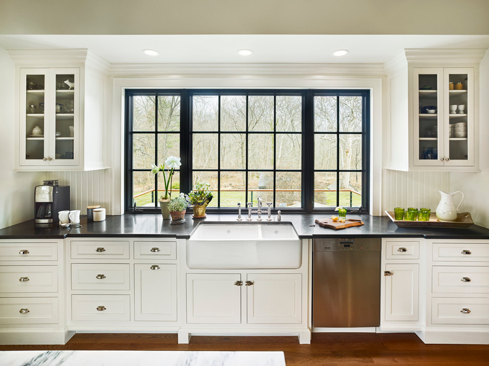 Large rural l-shaped kitchen/diner in Philadelphia with a submerged sink, recessed-panel cabinets, white cabinets, wood worktops, white splashback, stainless steel appliances, medium hardwood flooring and an island.