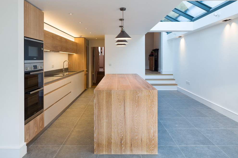 Kitchen - mid-sized contemporary single-wall kitchen idea in London with flat-panel cabinets, medium tone wood cabinets and an island