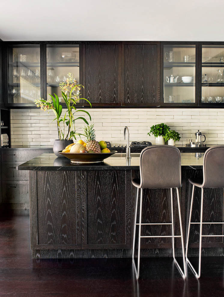 Modelo de cocina contemporánea con armarios tipo vitrina, puertas de armario de madera en tonos medios, salpicadero blanco, suelo de madera oscura y una isla