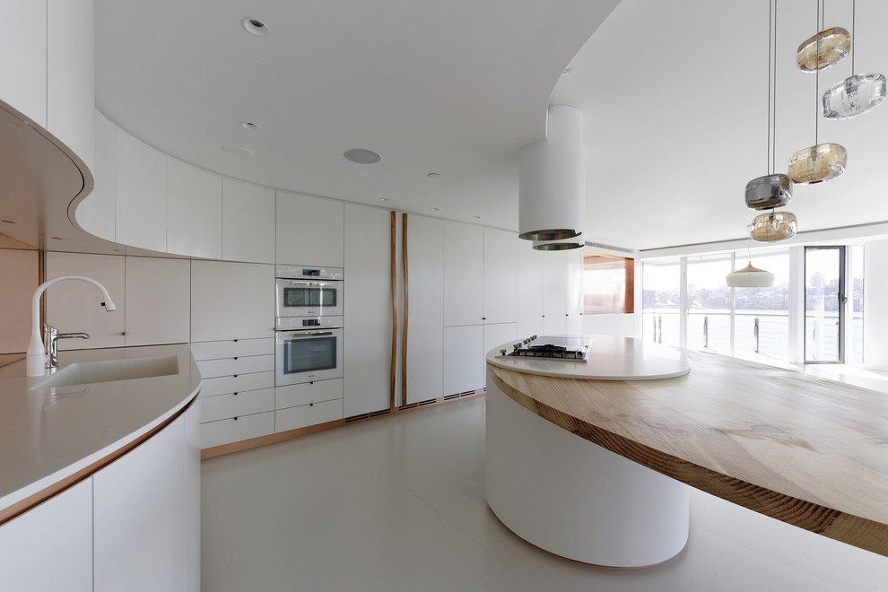 Modern inredning av ett stort kök, med en undermonterad diskho, släta luckor, vita skåp, bänkskiva i koppar, stänkskydd med metallisk yta, stänkskydd i metallkakel, vita vitvaror, klinkergolv i keramik, en köksö och beiget golv