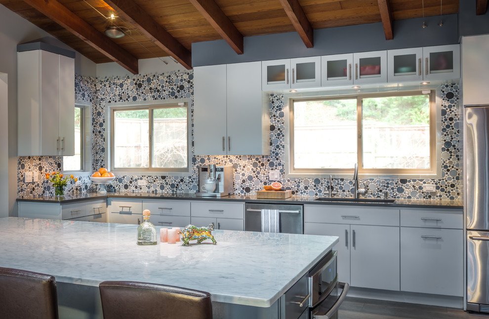 Bild på ett mycket stort retro kök, med en undermonterad diskho, släta luckor, grå skåp, bänkskiva i kvarts, flerfärgad stänkskydd, stänkskydd i keramik, rostfria vitvaror, mörkt trägolv och en köksö