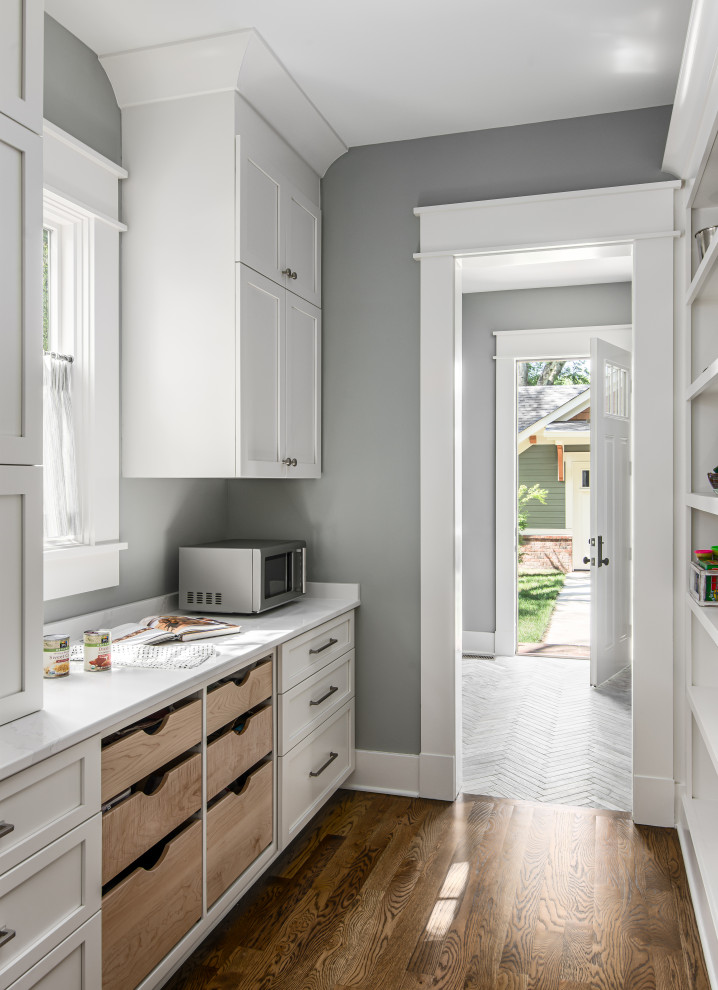 Photo of a mid-sized country l-shaped separate kitchen in Nashville with a farmhouse sink, shaker cabinets, white cabinets, quartz benchtops, white splashback, subway tile splashback, stainless steel appliances, dark hardwood floors, with island, white benchtop and exposed beam.