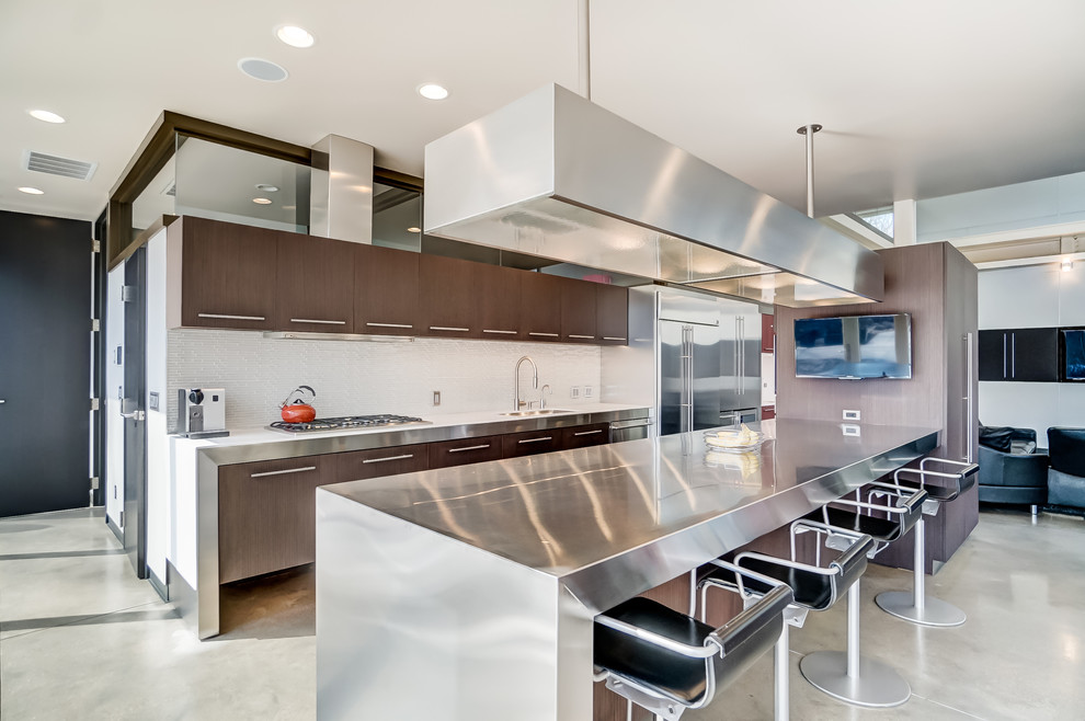 Inspiration for a contemporary single-wall concrete floor and gray floor open concept kitchen remodel in Cincinnati with an undermount sink, flat-panel cabinets, dark wood cabinets, stainless steel countertops, white backsplash, stainless steel appliances, an island and gray countertops