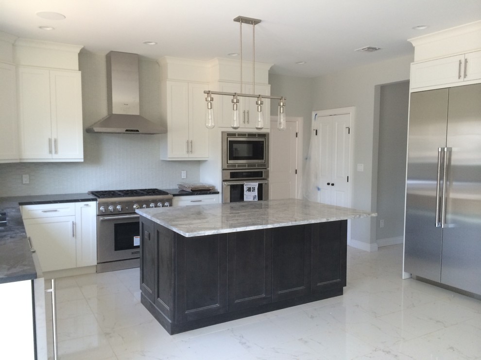 Inspiration for a large contemporary l-shaped marble floor and white floor kitchen remodel in New York with an undermount sink, shaker cabinets, white cabinets, gray backsplash, glass tile backsplash, stainless steel appliances and an island