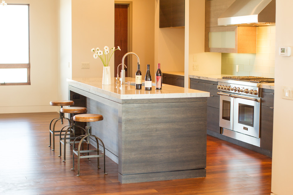 Example of a large trendy l-shaped bamboo floor open concept kitchen design in San Luis Obispo with an undermount sink, flat-panel cabinets, medium tone wood cabinets, quartzite countertops, green backsplash, glass tile backsplash, stainless steel appliances and an island