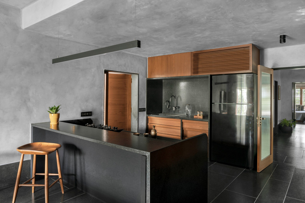Esempio di una cucina parallela design con ante lisce, ante in legno scuro, paraspruzzi grigio, elettrodomestici neri, penisola e top grigio