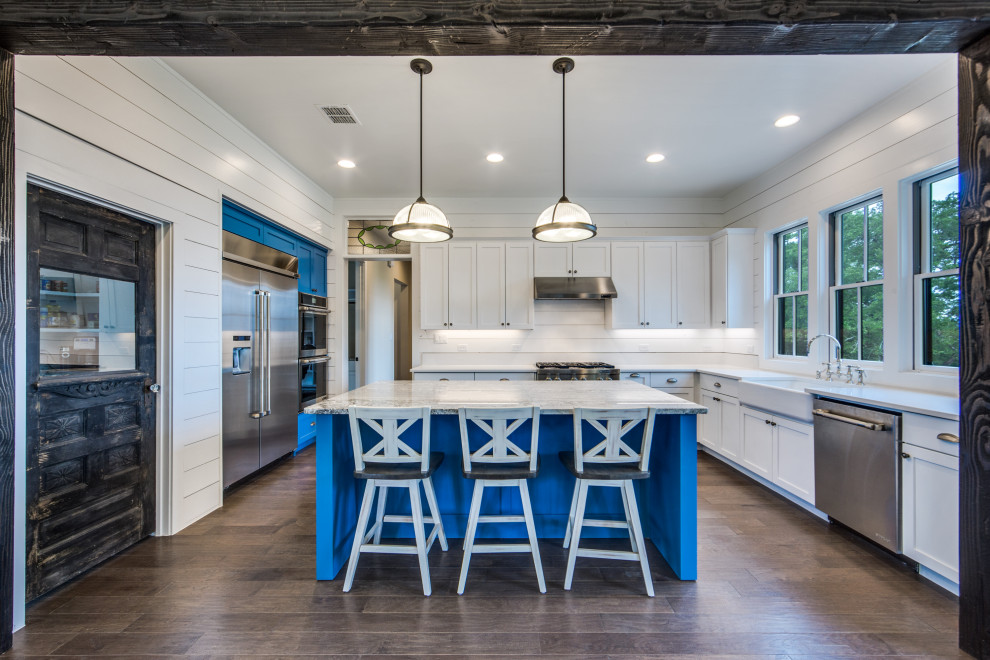 Large farmhouse u-shaped dark wood floor and brown floor eat-in kitchen photo in Dallas with a farmhouse sink, shaker cabinets, white cabinets, quartz countertops, white backsplash, shiplap backsplash, stainless steel appliances, an island and white countertops