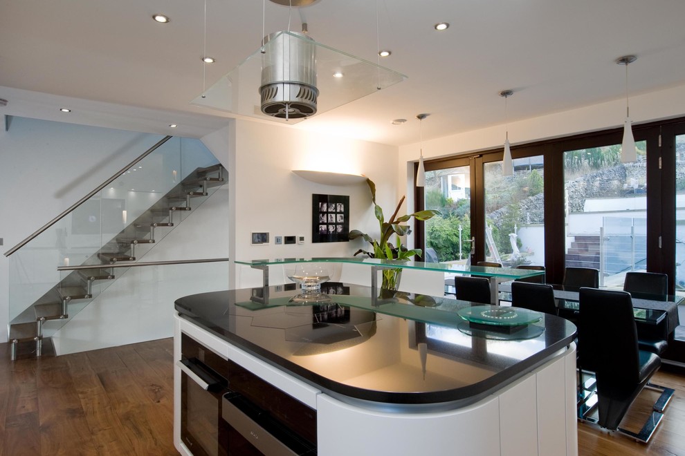 Design ideas for a contemporary kitchen/diner in Manchester with white cabinets, glass worktops and turquoise worktops.