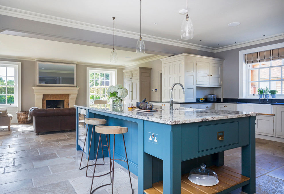 Inspiration for a large traditional u-shaped open plan kitchen in Hampshire with a belfast sink, flat-panel cabinets, granite worktops, mirror splashback, stainless steel appliances, limestone flooring, an island and beige floors.